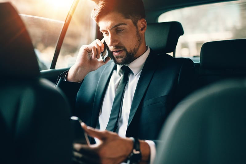 Ein Geschäftsmann sitzt im Taxi und führt ein Business Telefonat